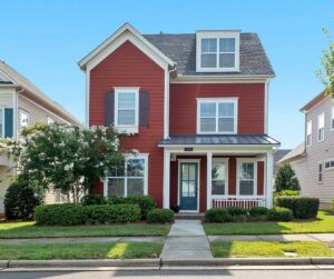 Suburban, 3-story home with red siding and black shutters.